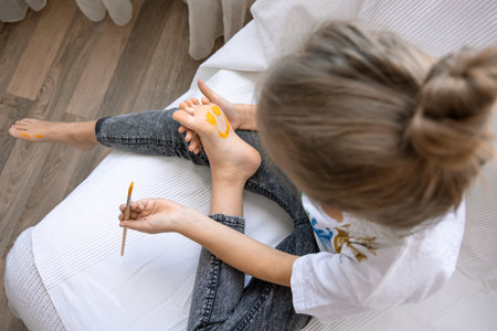 The child draws a pattern on his foot with a brush. Funny drawing with paints on the body.の写真素材