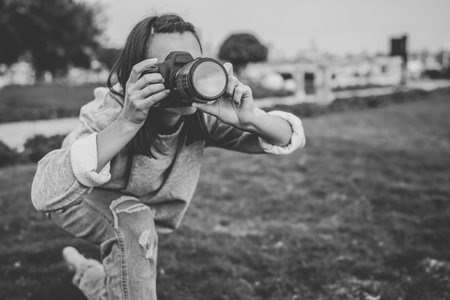 Girl makes a photo on a professional SLR camera in the summer outdoors.の写真素材