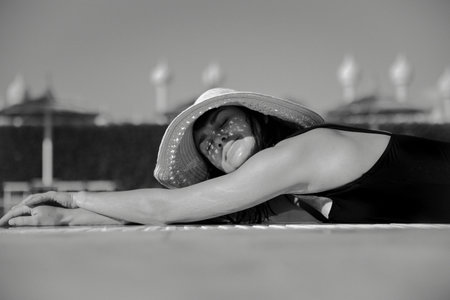 Attractive girl resting in the sun wearing a straw hat and a swimsuit. The concept of vacation in a...