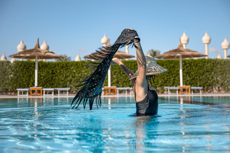 A girl in the pool on a hot sunny day. Concept of vacation and resort in a warm country.の写真素材