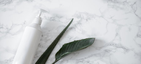 Care product and natural leaves on a marble surface. Health, beauty and personal hygiene concept.の写真素材