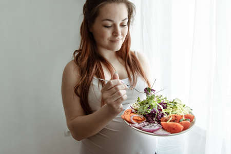 The expectant mother in the last months of pregnancy eats a salad of fresh vegetables.の写真素材