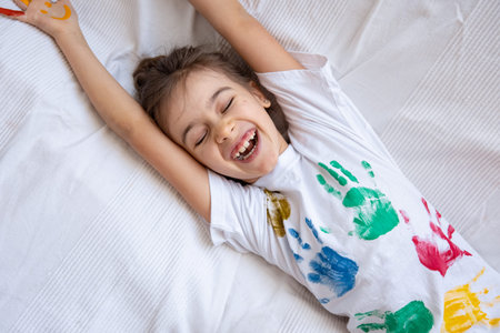 Little happy girl with painted t-shirt handprints close up. Children's creativity.