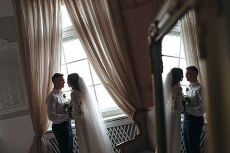 Cute portrait of the bride and groom by the window. Wedding photo session.の写真素材