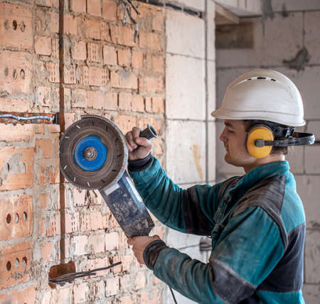 A professional builder in work clothes works with a cutting tool.の写真素材