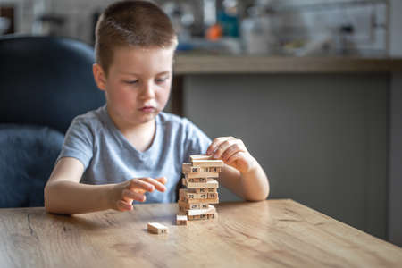 Focused little boy builds a turret with wooden cubes.の写真素材