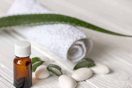 Close-up of a jar with natural oil for beauty and health on the background of aloe leaves with a towel.の写真素材