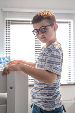 A cute little boy in his room is looking at the camera.の写真素材