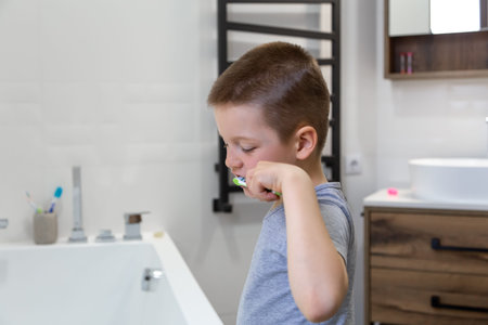 Cute little boy brushing teeth in a cozy bathroom interior.