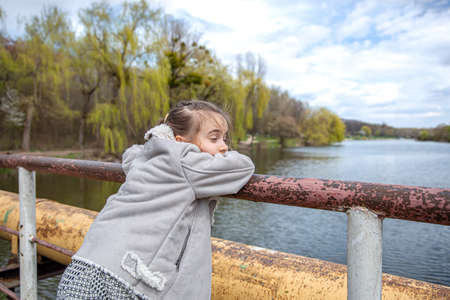 A little girl is looking somewhere for a walk in the caty park in early spring.の写真素材