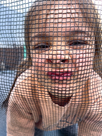 Little girl looks into the camera through the net.の写真素材