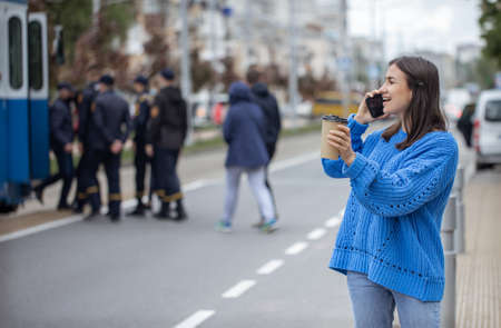 Street portrait of a young woman talking on the phone in the city near the roadway.の写真素材
