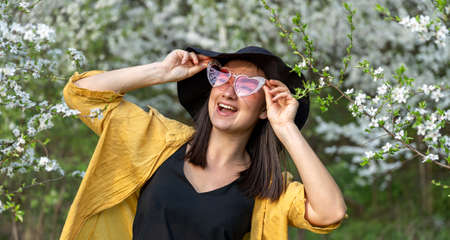 Portrait of a stylish girl among flowering trees in the forest.の写真素材