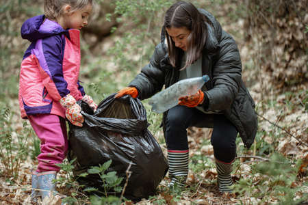 Mom and daughter clean the forest from plastic and other debris.の写真素材