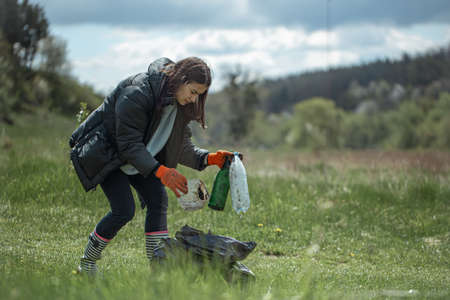 Girl volunteer collects garbage in the forest, takes care of the environment.の写真素材