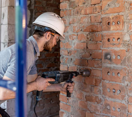 Close-up of the process of drilling a brick wall at a construction site.の写真素材