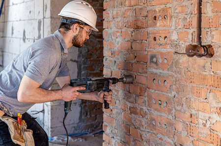 Close-up of the process of drilling a brick wall at a construction site.の写真素材