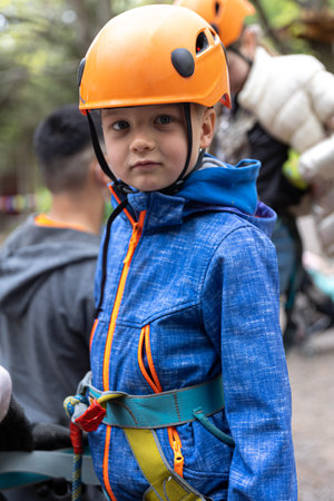 Adventure climbing high wire park - little boy on course in mountain helmet and safety equipment.
