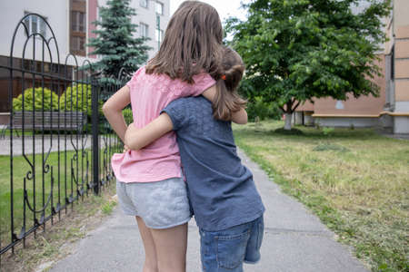 Two little girlfriends sisters hug on a walk in the summer.の写真素材