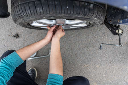 Close-up a man changes a wheel in a car on the road.の写真素材