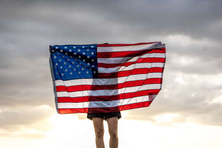 Young woman with United States flag enjoying sunset in nature.の写真素材