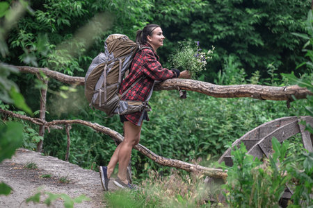 Attractive girl tourist with a large backpack for travel and with a bouquet of wildflowers.