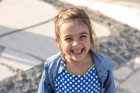 A cute little girl smiles and looks into the camera.