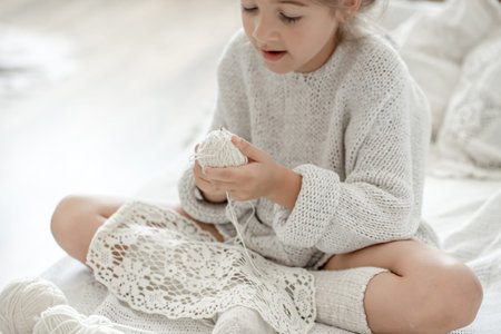 Little girl with a lace napkin from natural cotton yarn, crochet by hand. Crochet as a hobby.