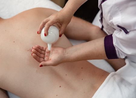 Massage therapist pours oil for massage, relaxing body massage using oils.の写真素材