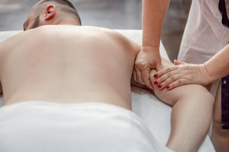Close-up of the hands of a female massage therapist in the process of kneading male hands.の写真素材