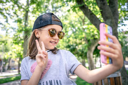Happy little girl in sunglasses makes a face and selfie.の写真素材