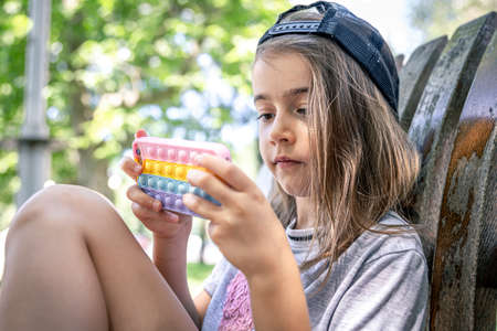 Little girl in a cap with a smartphone in a case in the style of toys anti stress.の写真素材
