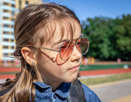 Little girl, primary school student in sunglasses, outdoor close-up.の写真素材