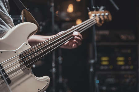 Close-up of a bass guitar in the hands of a musician in the process of playing.の写真素材