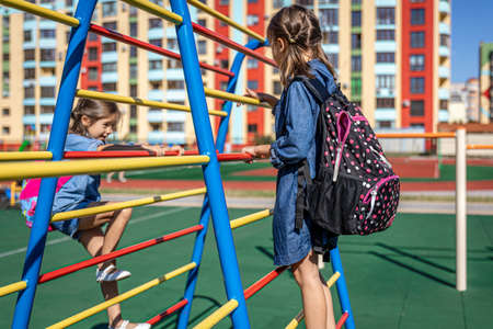 Two little girls, elementary school students, play on the playground after school.の写真素材