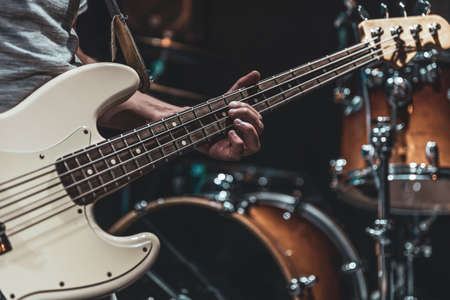 Close-up of a bass guitar in the hands of a musician in the process of playing.の写真素材