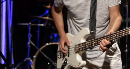 Bass guitarist plays the bass guitar in a dark room on a blurred background.の写真素材