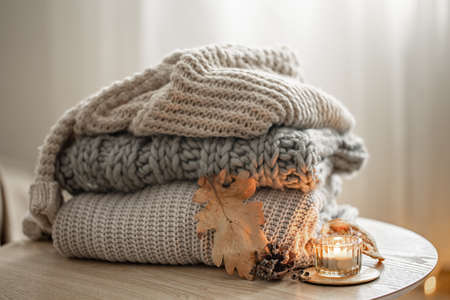 Autumn composition with cozy knitted sweaters in pastel shades and a dry leaf.の写真素材