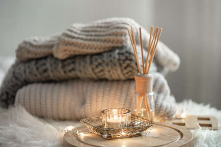 Aroma bamboo sticks in a bottle with scented liquid with candles staying on a wooden tray on blurred background.の写真素材