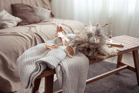 A bouquet of dry autumn flowers and a knitted sweater in the interior of the room.の写真素材