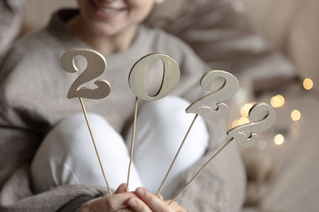 Close up of wooden numbers 2022 on sticks in female hands on blurred background with bokeh.の写真素材