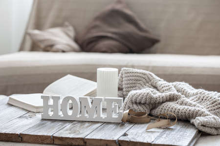 Decorative wooden word home, book, candle and knitted element on blurred background.の写真素材