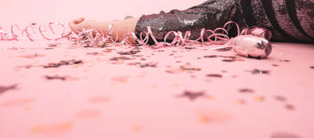 Part of the girl lying on a pink background among the serpentine and Christmas decor.の写真素材