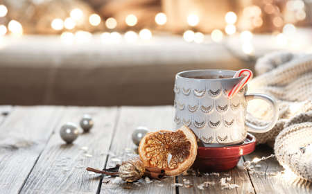 Cozy Christmas background with a cup, knitted element and blurry lights, winter mood, home comfort.の写真素材