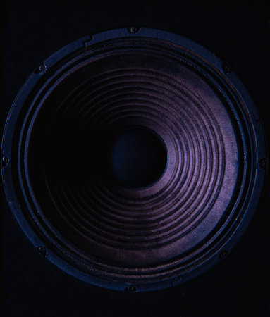 Close-up of speaker membrane on black background with colored lighting.の写真素材