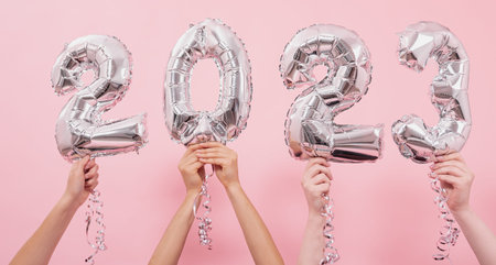 Happy New year 2023 celebration. Silver foil balloons numeral 2023 on a pink background.