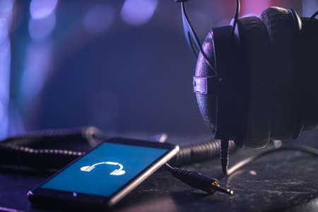 Phone with music icon and headphones on blurred background, music listening concept, copy space.の写真素材