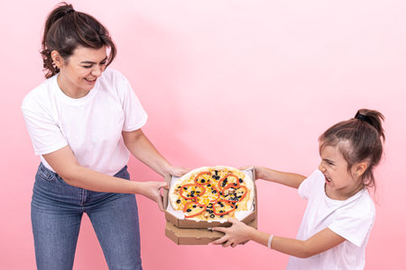 A little girl takes pizza from an adult sister, girls cannot share pizza among themselves, pink...