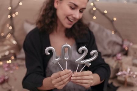 Young woman holding candles in the form of numbers 2022, new year celebration concept.