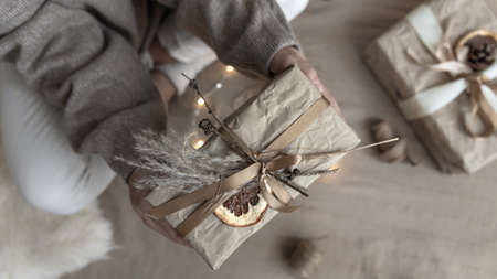 Close-up of a Christmas present, decorated with dried flowers and a dry orange, wrapped in craft paper.の写真素材